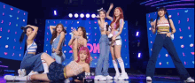 a group of girls are standing on a stage in front of a blue screen that says the show