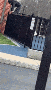 a man climbs over a fence with a sign on it that says no dogs