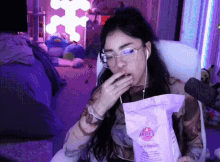 a woman eating a bag of angie 's popcorn