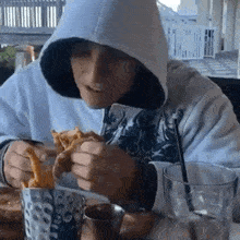 a man in a hoodie is eating french fries