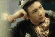 a man wearing a crown and a suit is sitting down .