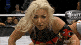 a woman is kneeling down in a wrestling ring with a sign that says draft kings on it .