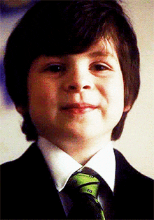 a young boy is wearing a suit and tie