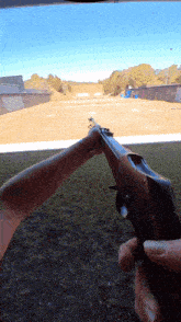 a person is holding a gun in front of a field