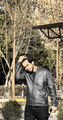 a man in a leather jacket holds a pair of sunglasses in his hand
