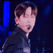a close up of a person wearing a microphone on a stage with their eyes closed .