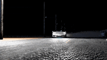a white porsche is driving down a dark street at night