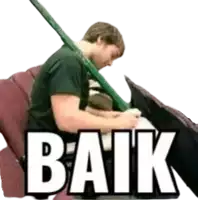 a man is sitting in a chair with a green stick in his mouth and the word baik written below him