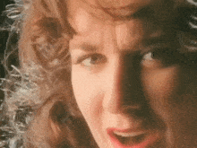a close up of a woman 's face with curly hair and red lipstick .