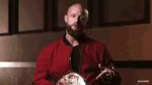 a bald man with a beard is wearing a red jacket with the word longest written on it