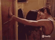 a man and a woman are kissing in a bathroom with abc family in the corner