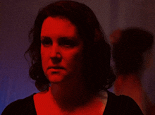 a woman in a dark room with a red light shining on her face