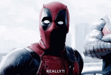 deadpool is wearing a mask and talking to a man in a spiderman suit .