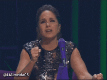 a woman sitting in front of a microphone with the hashtag lialmeida05 on the bottom right