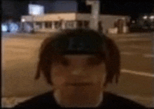 a man with dreadlocks is wearing a headband and standing in front of a building .