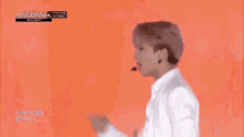 a man in a white shirt is dancing on a stage in front of a red background .