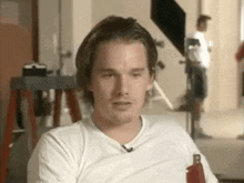 a man wearing a white shirt is sitting in a chair .