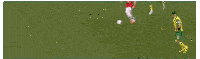a blurry picture of a soccer field with a goalie in the foreground and a player in the background
