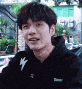 a young man wearing a black hoodie that says amens on it