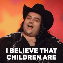 a man with long hair wearing a cowboy hat and a jacket says i believe that children are