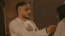 a man in a white shirt is holding another man 's arm