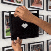 a person is putting a picture frame on a wall with pictures on it