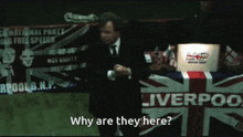 a man in a suit stands in front of a sign that says liverpool