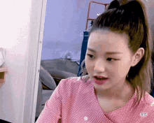 a girl with a ponytail is wearing a plaid shirt