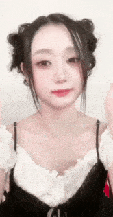 a close up of a woman 's face wearing a white top and black tank top .