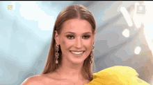 a woman wearing a yellow dress and earrings smiles for the camera .