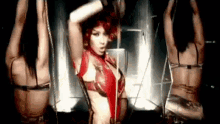 a woman in a red bodysuit is dancing with two other women in a dark room .