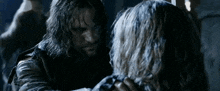 a man with long hair and a beard holds a woman 's hand
