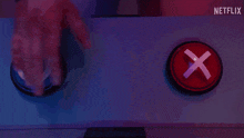 a person is pressing a red button with an x in it