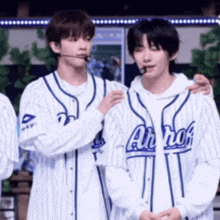 two baseball players are standing next to each other and one of them is wearing a jersey that says alcohol .
