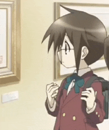 a boy in a school uniform is standing in front of a wall with paintings .