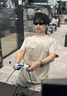 a man wearing sunglasses is holding a controller