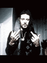 a man wearing a louis vuitton scarf shows his middle finger