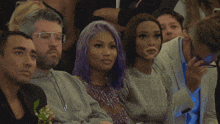 a woman with purple hair sits next to a man in a suit