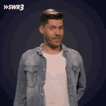 a man in a denim shirt is standing in front of a blue background with the letters swr3 on it