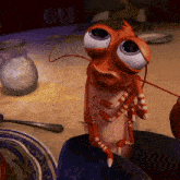 a cartoon lobster with big eyes sits on a table