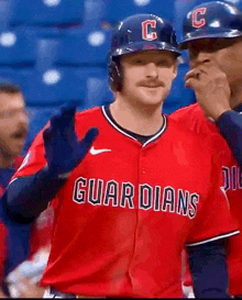 a baseball player wearing a red uniform with the word guardians on it