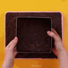 a person is holding a square shaped cookie cutter over a brownie