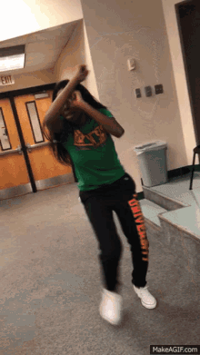 a girl in a green shirt and black pants with university written on them