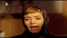 a woman wearing a scarf around her head is singing .