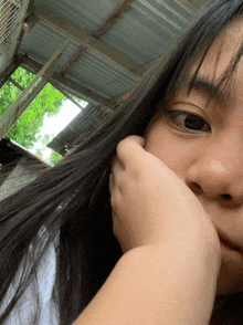 a girl covering her mouth with her hand while looking at the camera