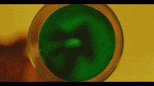 a green liquid in a glass on a yellow surface