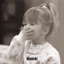 a little girl covering her mouth with her hand and the words diolch on the bottom left