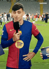 a man in a soccer uniform is holding a microphone on a field