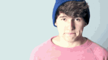 a man wearing a pink shirt and a blue hat