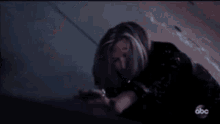 a man with long hair and a beard is laying on a bed in the dark .